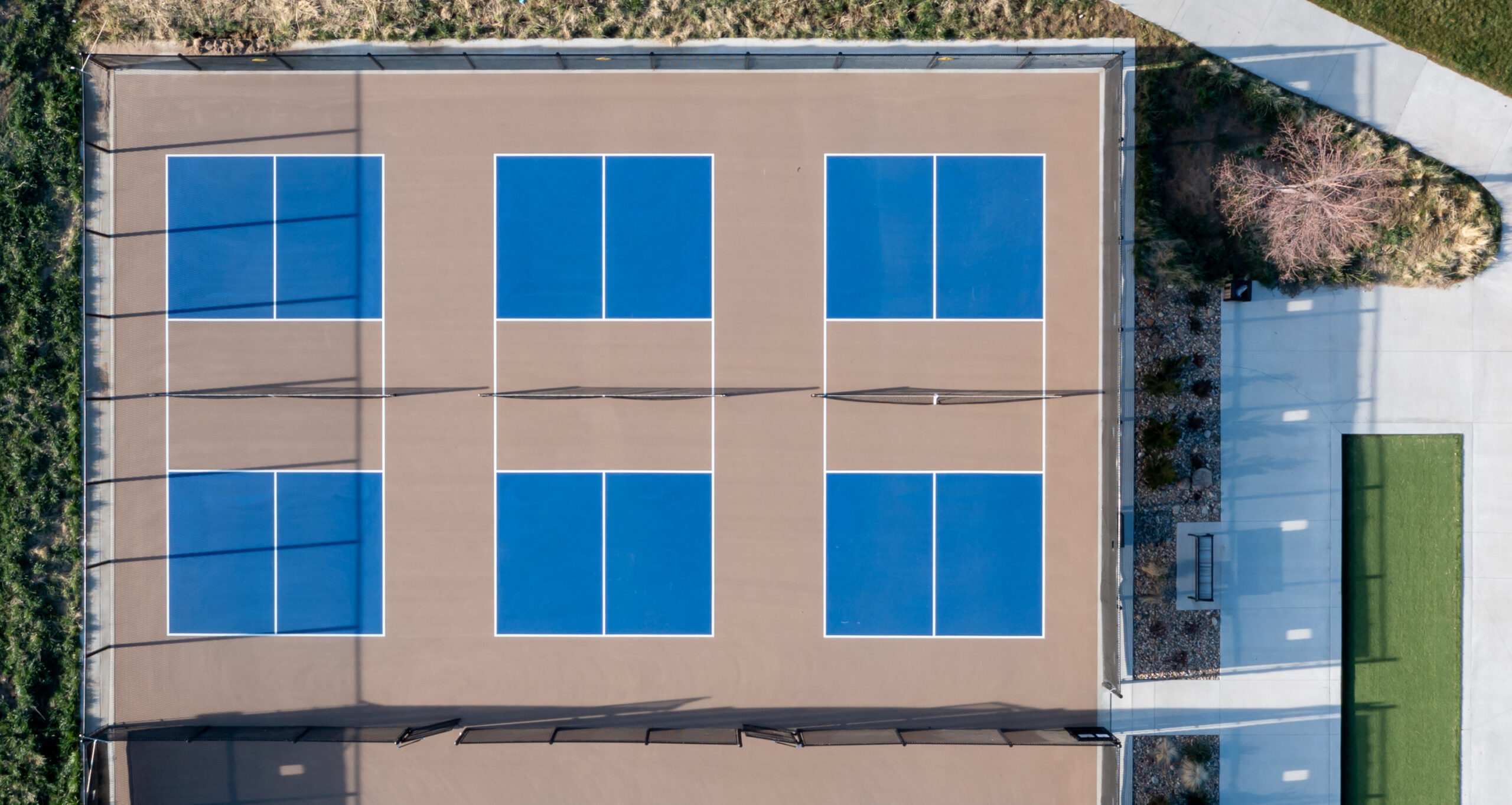 Overhead aerial of multiple pickle ball fields with some landsca