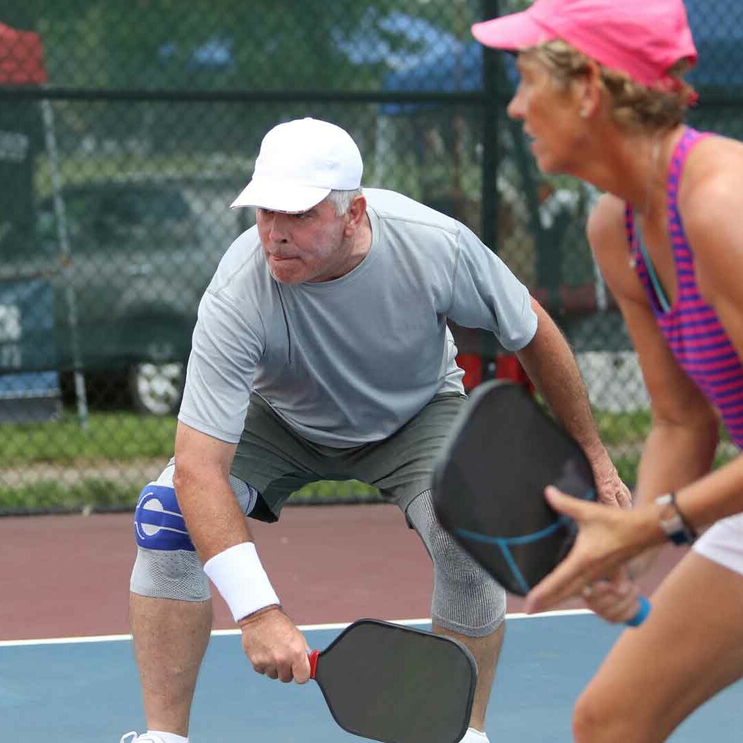 Adults playing pickle ball at community clubhouse